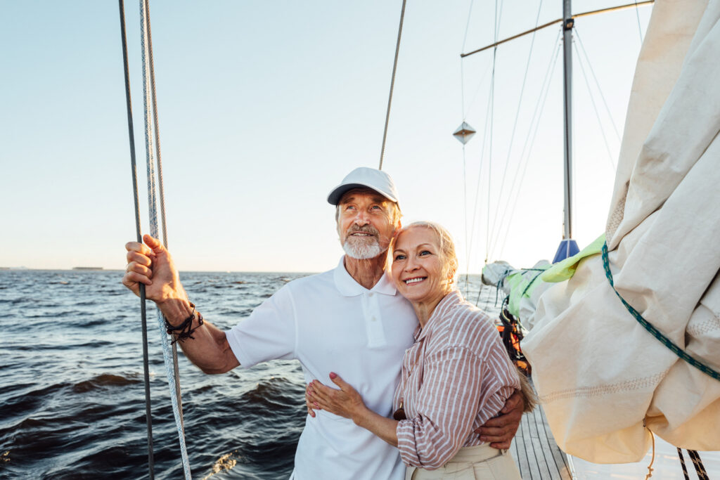 Loving senior couple enjoying vacation and looking to the distance. Mature couple standing together and embracing on a private sailboat. An older couple enjoys their time on a sail boat.